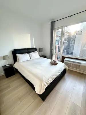 a bedroom with a large bed and a large window at 5 mins to Midtown Central New Luxury Corner 2b2b Apt with Amazing City View in Long Island City