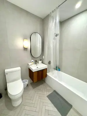 a bathroom with a toilet and a sink and a mirror at 5 mins to Midtown Central New Luxury Corner 2b2b Apt with Amazing City View in Long Island City
