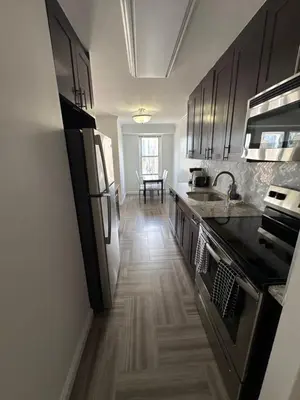 a kitchen with black appliances and a wooden floor at Midtown High Floor Fantastic Panoramic City View Corner 2 Bedroom Apartment in New York