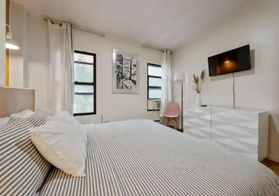 a white bedroom with a bed and a tv on the wall at Three Bedroom Rental in Midtown West , June to Aug 90 days stay required in New York