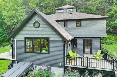 a gray house with green chairs on a balcony at 8 Mi to Tanglewood and Butternut Ski Spacious Home! in Housatonic