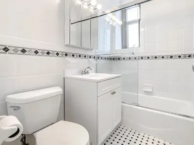 a white bathroom with a toilet and a sink at Midtown Park Ave Charming Chrysler View Corner Studio in New York