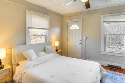 a bedroom with a white bed and two windows at Walk to Dtwn Hudson Cozy Upstate Apartment in Hudson