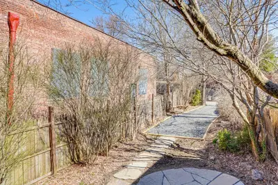 a brick building with a fence next to a sidewalk at Walk to Dtwn Hudson Cozy Upstate Apartment in Hudson