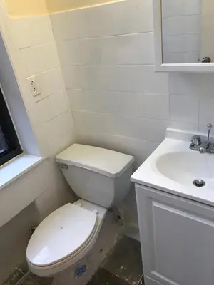 a white bathroom with a toilet and a sink at Great Looking Studio Apartment in New York