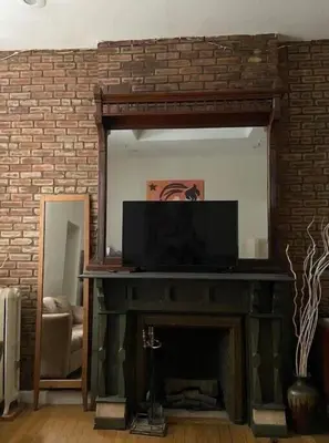 a living room with a fireplace and a mirror at Great Looking Studio Apartment in New York