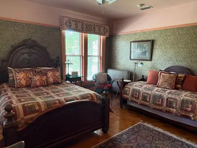 a bedroom with two beds and a chair and a window at Amherst Inn in Amherst