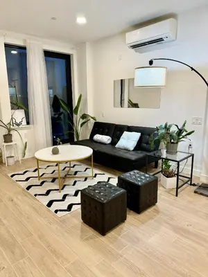a living room with a black couch and a table at Peaceful Quiet Spacious New Modern Penthouse 3-Bedroom Apartment with a Balcony in Brooklyn
