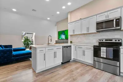 a kitchen with white cabinets and a blue couch at Stylish Comfort Wooster Square Yale Wi-Fi in New Haven