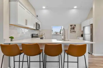 a kitchen with a white counter and orange chairs at Stylish Comfort Wooster Square Yale Wi-Fi in New Haven