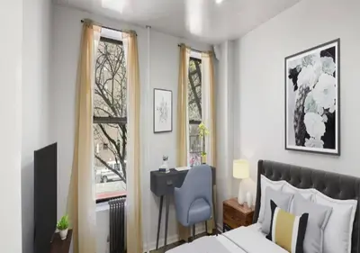 a bedroom with a bed and a desk and two windows at Upper E Side Spacious Studio! in New York