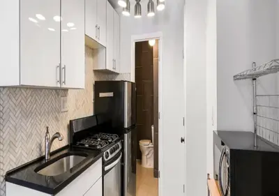 a white kitchen with a sink and a stove at Upper E Side Spacious Studio! in New York