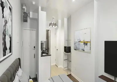 a living room with white walls and a television at Upper E Side Spacious Studio! in New York