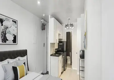 a bedroom with a bed and a small kitchen at Upper E Side Spacious Studio! in New York