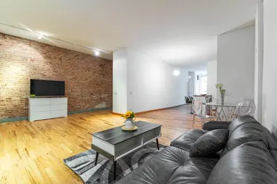 a living room with a leather couch and a brick wall at XL Prime Tribeca Furnished Loft, June To Aug 90 Days Stay Required in New York