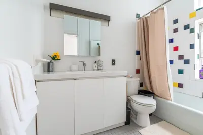 a white bathroom with a sink and a toilet at XL Prime Tribeca Furnished Loft, June To Aug 90 Days Stay Required in New York