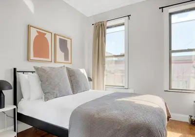 a white bedroom with a bed and two windows at Midtown West Furnished Apartment 3BR in New York
