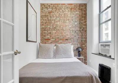 a bedroom with a brick wall and a bed at Midtown West Furnished Apartment 3BR in New York