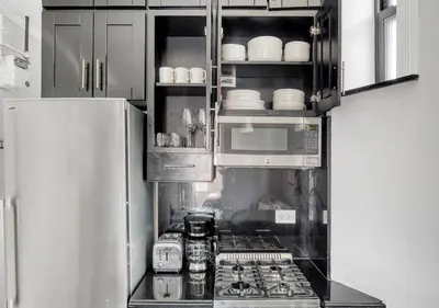 a kitchen with a stove and a microwave at Midtown West Furnished Apartment 3BR in New York