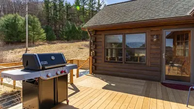 a barbecue on a deck next to a cabin at Secluded w Deck Views Hot Tub Ping Pong Hudson in the Berks by AvantStay in East Chatham