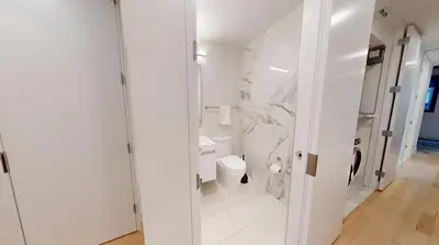 a white bathroom with a toilet and a shower at Sleek Two Bedroom in Manhattan in New York