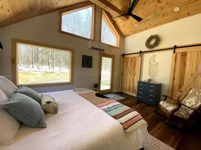 a bedroom with a large bed and two windows at The A-Frame at Harvest Moon Acres in Stamford