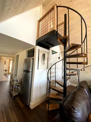 a spiral staircase in a living room next to a refrigerator at The A-Frame at Harvest Moon Acres in Stamford