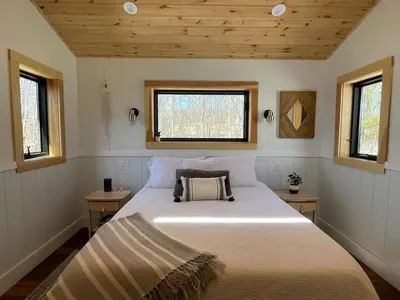 a bedroom with a large bed with two windows at The A-Frame at Harvest Moon Acres in Stamford