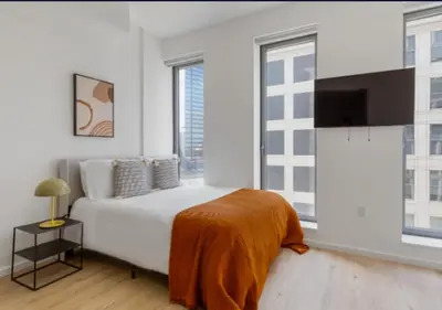 a white bedroom with a bed and a flat screen tv at Awesome Sunny Studio! Best Location! in New York
