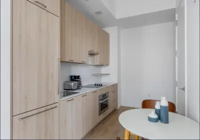 a kitchen with wooden cabinets and a white table at Awesome Sunny Studio! Best Location! in New York