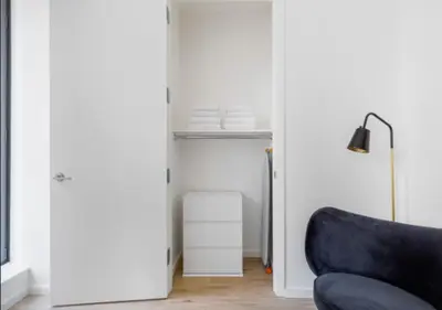 a living room with a blue chair and a closet at Awesome Sunny Studio! Best Location! in New York