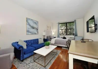 a living room with a blue couch and a bed at Charming UES Studio, Walk to Subway & Central Park, June To Aug 90 Days Stay Required in New York