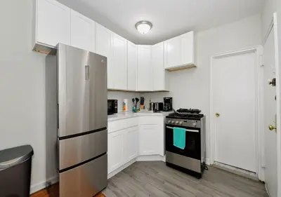 a kitchen with white cabinets and a stove top oven at Charming UES Studio, Walk to Subway & Central Park, June To Aug 90 Days Stay Required in New York