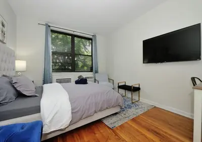 a bedroom with a bed and a flat screen tv at Charming UES Studio, Walk to Subway & Central Park, June To Aug 90 Days Stay Required in New York