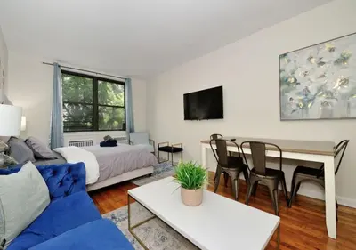 a living room with a blue couch and a table at Charming UES Studio, Walk to Subway & Central Park, June To Aug 90 Days Stay Required in New York