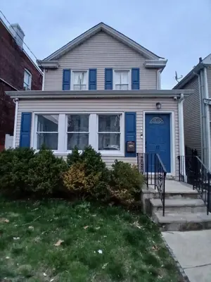 a house with a blue door on a street at Monthly Stays - 2BR Apt in Bloomfield - 8 Min Walk from NJ Transit in Bloomfield