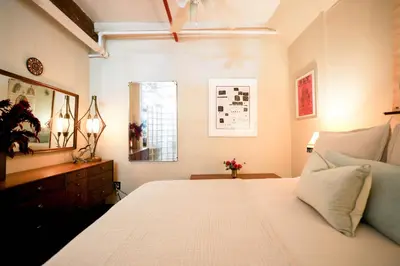 a bedroom with a large white bed and a window at Artistic Vintage Loft in Williamsburg in Brooklyn