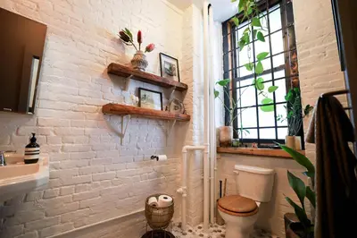 a bathroom with a white brick wall and a toilet at Artistic Vintage Loft in Williamsburg in Brooklyn