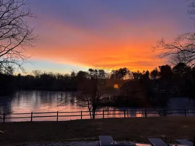 a sunset over a body of water with a fence at Room in Lake Home - 2BR 1BA Kitchenette in Greenwich