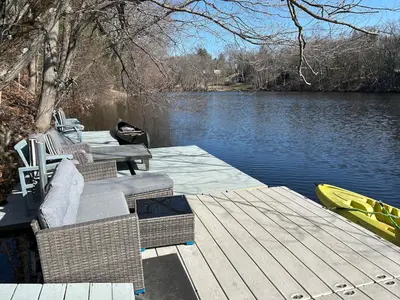 a wooden dock with chairs and a boat on a lake at Room in Lake Home - 2BR 1BA Kitchenette in Greenwich