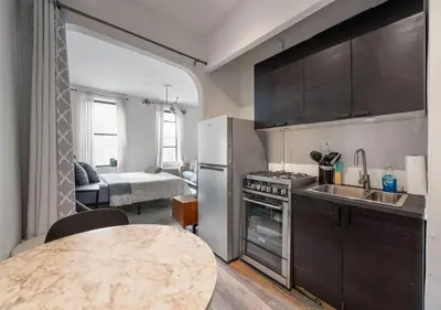 a kitchen with a table and a room with a bed at Prime Murray Hill 2 BR Gem, June To Aug 90 Days Stay Required in New York