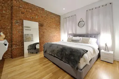 a bedroom with a large bed and a brick wall at Spacious 2BR 2BA with Rooftop Walk to Times Square, June To Aug 90 Days Stay Required in New York