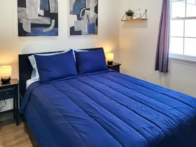 a large blue bed in a bedroom with two lamps at Spacious 2-BR 1-Bath King suite! in Plainville