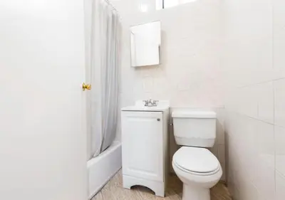 a white bathroom with a toilet and a sink at Prime Location Upper Manhattan Furnished Apartment, June To Aug 90 Days Stay Required in New York