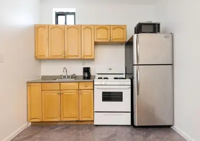 a kitchen with a white refrigerator and wooden cabinets at Prime Location Upper Manhattan Furnished Apartment, June To Aug 90 Days Stay Required in New York