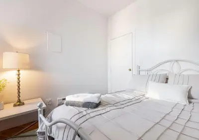 a white bedroom with a white bed and a lamp at Prime Location Upper Manhattan Furnished Apartment, June To Aug 90 Days Stay Required in New York