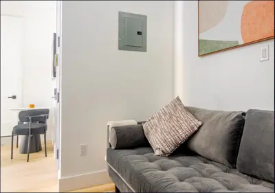 a living room with a gray couch and a table at Murray Hill 1 Bed Furnished Apt in New York