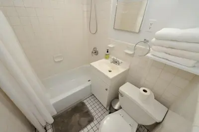 a white bathroom with a toilet and a sink at Prime Location Murray Hill! Grand Central Station!, June To Aug 90 Days Stay Required in New York