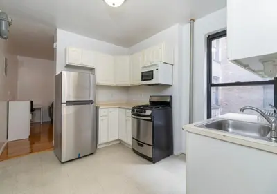 a kitchen with white cabinets and a stainless steel refrigerator at Murray Hill and Kips Bay! Amazing 1BR for 2! in New York