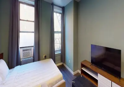 a bedroom with a bed and a flat screen tv at Amazing Studio in Kips Bay! in New York